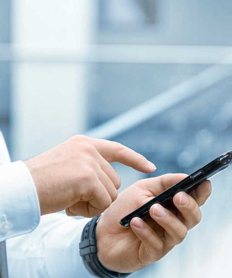 Eine Hand zeigt auf ein Mobiltelefon.