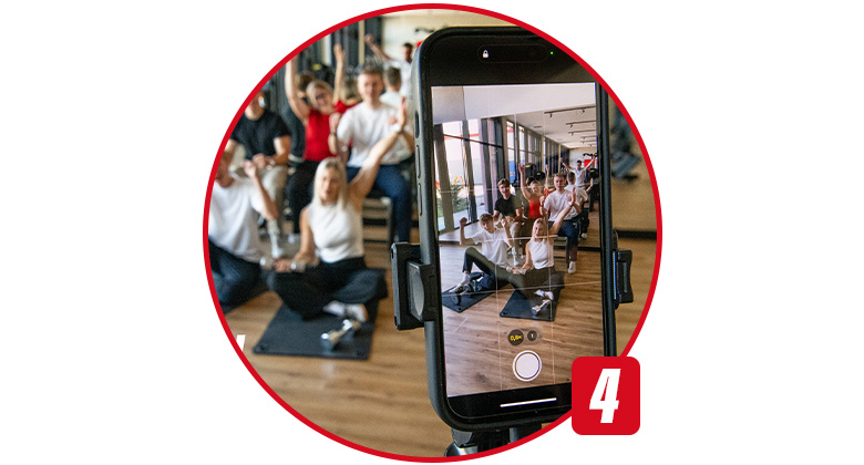 A group poses on exercise mats, captured through a smartphone on a tripod.
