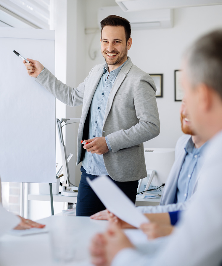 Photo of a man that points to a flipchart.